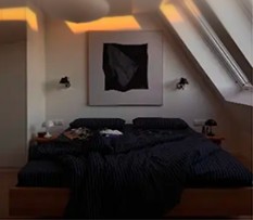 Bedroom with dark bedding under an abstract artwork
