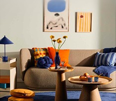 Living room with a beige sofa, bright cushions, and round side tables
