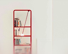 Red wall shelf holding books